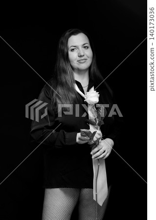 portrait of a woman in a black shirt with a white tie holding a rose on a dark background portrait of a woman in a black shirt with a white tie holding a rose on a dark background 140173036