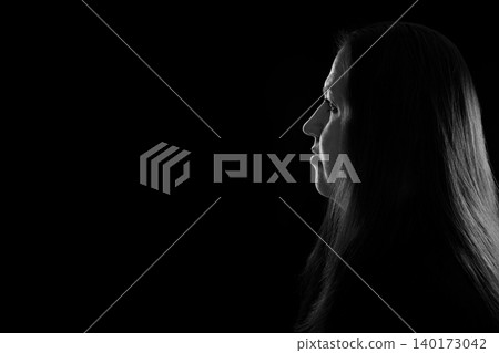 black and white contrast portrait of a female profile in the dark with a light outline on her hair black and white contrast portrait of a female profile in the dark with a light outline on her hair 140173042