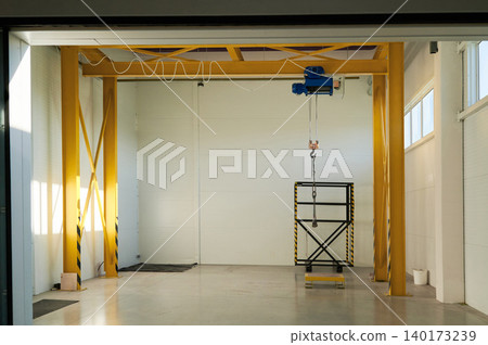 Bright industrial space with a hoist in use 140173239