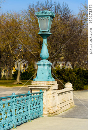 Charming blue lamp post lights up the park path 140173273