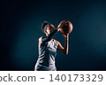 A female basketball player prepares to throw a ball against black background 140173329