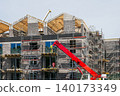 Residential apartment building under construction with scaffolding, crane and timber roof framing 140173349