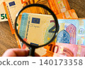 Magnifying glass examining euro banknotes for finance, money security and fraud detection analysis 140173358