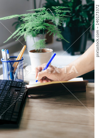 A man writes in a notebook and makes a business plan A man writes in a notebook and makes a business plan 140173372