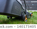 Close up of lawn mower side and wheel on backyard grass near fence 140173405