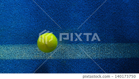 Close-up of a tennis or padel ball bouncing on a blue court surface near the line. High-speed sports action captured in detail, ideal for competition, training and athletic concepts. Close-up of a tennis or padel ball bouncing on a blue court surface near the line. High-speed sports action captured in detail, ideal for competition, training and athletic concepts. 140173750