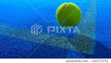 Close-up of a tennis or padel ball bouncing on a blue court surface near the line. High-speed sports action captured in detail, ideal for competition, training and athletic concepts. 140173752