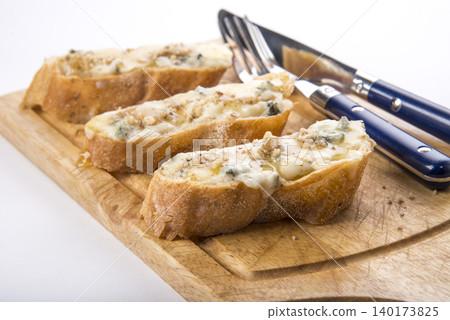 Savory garlic bread topped with cheese and herbs on a wooden cutting board Savory garlic bread topped with cheese and herbs on a wooden cutting board 140173825
