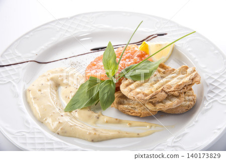 Delightful gourmet dish with salmon and creamy sauce served elegantly on a white plate Delightful gourmet dish with salmon and creamy sauce served elegantly on a white plate 140173829