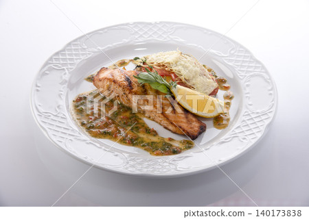 Delicious grilled salmon served with lemon and fresh herbs on a beautiful white plate Delicious grilled salmon served with lemon and fresh herbs on a beautiful white plate 140173838