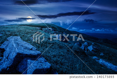 Carpathian mountain summer landscape at night. full moon over meadow with huge stones among the grass on top of the hillside near the peak of mountain range. mysterious alpine meadow and rolling hills Carpathian mountain summer landscape at night. full moon over meadow with huge stones among the grass on top of the hillside near the peak of mountain range. mysterious alpine meadow and rolling hills 140173893