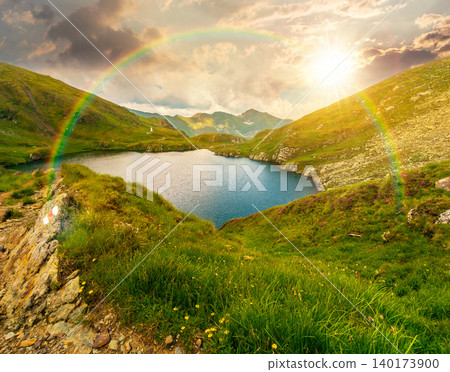 sunset over lovely summer scenery of alpine capra lake with steep slopes. nice view of transylvania alps, sibiu county. southern carpathian mountains of romania travel background with rainbow sunset over lovely summer scenery of alpine capra lake with steep slopes. nice view of transylvania alps, sibiu county. southern carpathian mountains of romania travel background with rainbow 140173900
