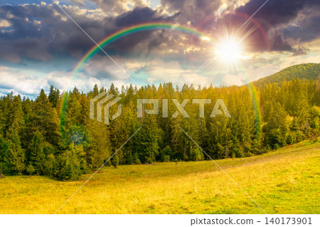 sunset over nature scenery with coniferous forest in mountain. carpathian landscape with spruce woodland on the hill. ukraine nature background in early autumn. weather with rainbow sunset over nature scenery with coniferous forest in mountain. carpathian landscape with spruce woodland on the hill. ukraine nature background in early autumn. weather with rainbow 140173901