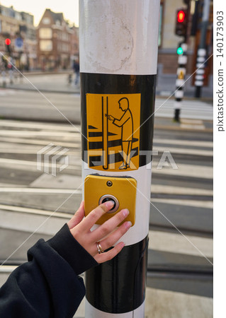 Busy Pedestrian Presses Button to Cross the Street in Amsterdam's Vibrant City Center Busy Pedestrian Presses Button to Cross the Street in Amsterdam's Vibrant City Center 140173903