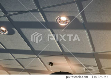 Unique Ceiling Design With Modern Lights Casting Intriguing Shadows in a Cafe Setting in Vibrant City Center Unique Ceiling Design With Modern Lights Casting Intriguing Shadows in a Cafe Setting in Vibrant City Center 140173945