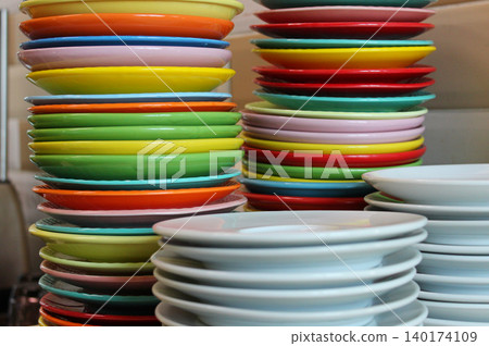 Multi colored plates stacked in columns according to size after a children's party Multi colored plates stacked in columns according to size after a children's party 140174109