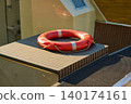 Bright Red Lifebuoy Resting on a Boat Deck a Sunny Day 140174161