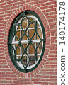 Charming Oval Window With Decorative Ironwork Graces a Historic Brick Building in Vibrant City Center 140174178