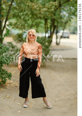 smiling blonde woman full length portrait outdoors smiling blonde woman full length portrait outdoors 140174238