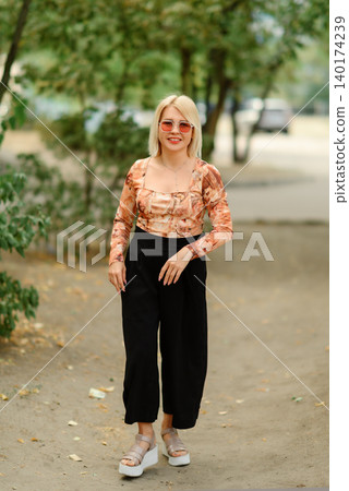 adult blonde woman walking on a path in a summer park adult blonde woman walking on a path in a summer park 140174239