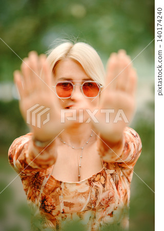 woman holding two palms out in front of her face outdoors woman holding two palms out in front of her face outdoors 140174240