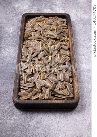 Sunflower seeds filling wooden bowl with healthy snack Sunflower seeds filling wooden bowl with healthy snack 140174705