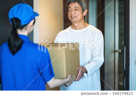 一位老年男子在公寓大樓門口接收包裹 140174923