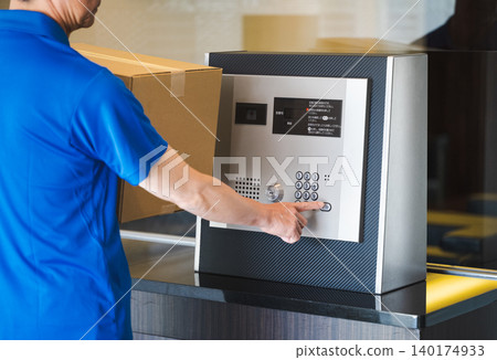 送貨員按下公寓大樓的對講機。 送貨員按下公寓大樓的對講機。 140174933