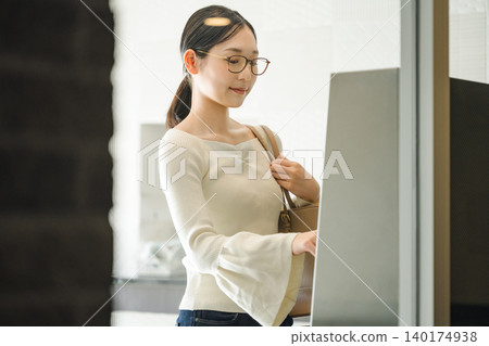 一名年輕女子正在操作公寓大樓的自動計時器。 一名年輕女子正在操作公寓大樓的自動計時器。 140174938