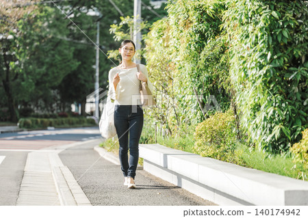 走在一個住宅區的年輕女子 走在一個住宅區的年輕女子 140174942