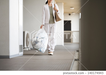 一位職業婦女正在公寓大樓倒垃圾。 一位職業婦女正在公寓大樓倒垃圾。 140174943