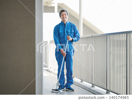 一位資深的男性建築管理員正在清潔公寓大樓的地板。 一位資深的男性建築管理員正在清潔公寓大樓的地板。 140174965