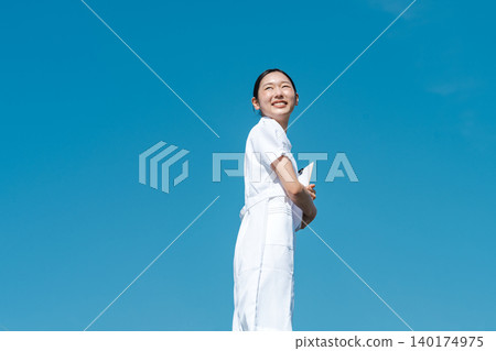 一位年輕的護士站在藍天下。 一位年輕的護士站在藍天下。 140174975