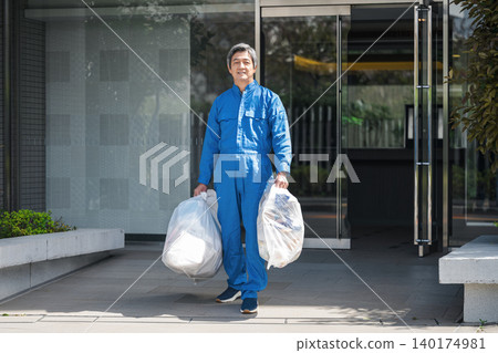 A senior male apartment building manager taking out the trash A senior male apartment building manager taking out the trash 140174981