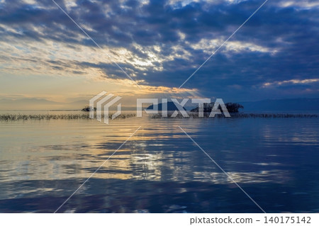 The light shining on Lake Biwa at sunset and the silhouette of the tranquil Chikubu Island. The light shining on Lake Biwa at sunset and the silhouette of the tranquil Chikubu Island. 140175142