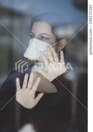A woman staying at home in quarantine and watching the outside world through the window A woman staying at home in quarantine and watching the outside world through the window 140175165