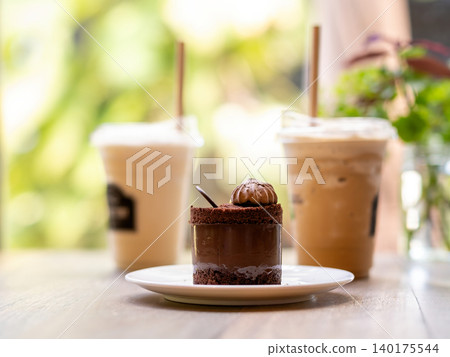 Chocolate mousse cake served with iced coffee drinks on a wooden cafe table, featuring rich dessert presentation, cozy coffee shop atmosphere, sweet indulgence, gourmet pastry and relaxing lifestyle 140175544
