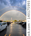 A double rainbow appeared in the sky after the rain, and the parking lot was wet. 140175993