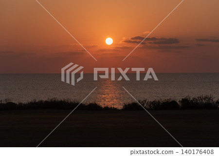 The orange sunset sky with land in the foreground and the clearly defined horizon of the sea. The orange sunset sky with land in the foreground and the clearly defined horizon of the sea. 140176408