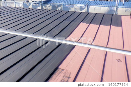 A renovation site where a sheet metal roof of a house is being painted. A renovation site where a sheet metal roof of a house is being painted. 140177324