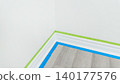 Interior corner of a room with painter's tape applied to walls and floor, preparing for painting or renovation project in a residential setting 140177576