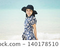 一位戴著草帽的年輕女子沿著海灘行走 140178510