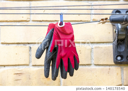 Red gardening gloves on a clothesline after being washed Red gardening gloves on a clothesline after being washed 140178540