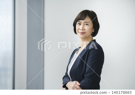 一位資深女商人面帶微笑地直視鏡頭，拍攝了她的肖像照。 140178665
