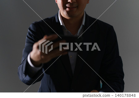 一張照片顯示,一名男子在昏暗的房間裡使用智慧型手機觀看來自非法上傳網站的影片和圖片。 一張照片顯示,一名男子在昏暗的房間裡使用智慧型手機觀看來自非法上傳網站的影片和圖片。 140178848