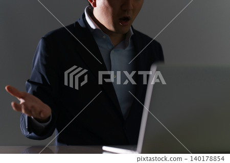 一位三十多歲、穿著西裝、面容模糊的男子,在昏暗的房間裡盯著筆記型電腦,對意想不到的情況感到驚訝。 一位三十多歲、穿著西裝、面容模糊的男子,在昏暗的房間裡盯著筆記型電腦,對意想不到的情況感到驚訝。 140178854