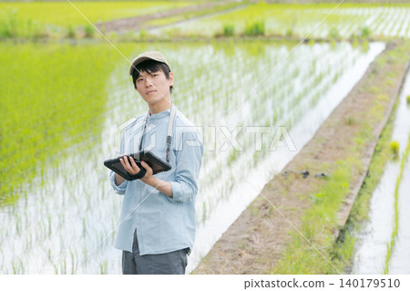 A young man uses a tablet to farm. 140179510