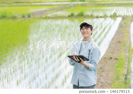 A young man uses a tablet to farm. A young man uses a tablet to farm. 140179515