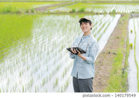 一位年輕人用平板電腦務農。 一位年輕人用平板電腦務農。 140179549