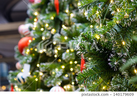 green christmas tree branch with fake white snow on tips. warm glowing hexagon bokeh lights in blurred background green christmas tree branch with fake white snow on tips. warm glowing hexagon bokeh lights in blurred background 140179609